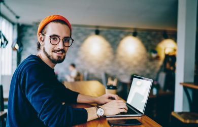 cheerful-hipster-blogger-sitting-in-cafe-with-mock-2025-03-26-18-08-58-utc cheerful-hipster-blogger-sitting-in-cafe-with-mock-2025-03-26-18-08-58-utc